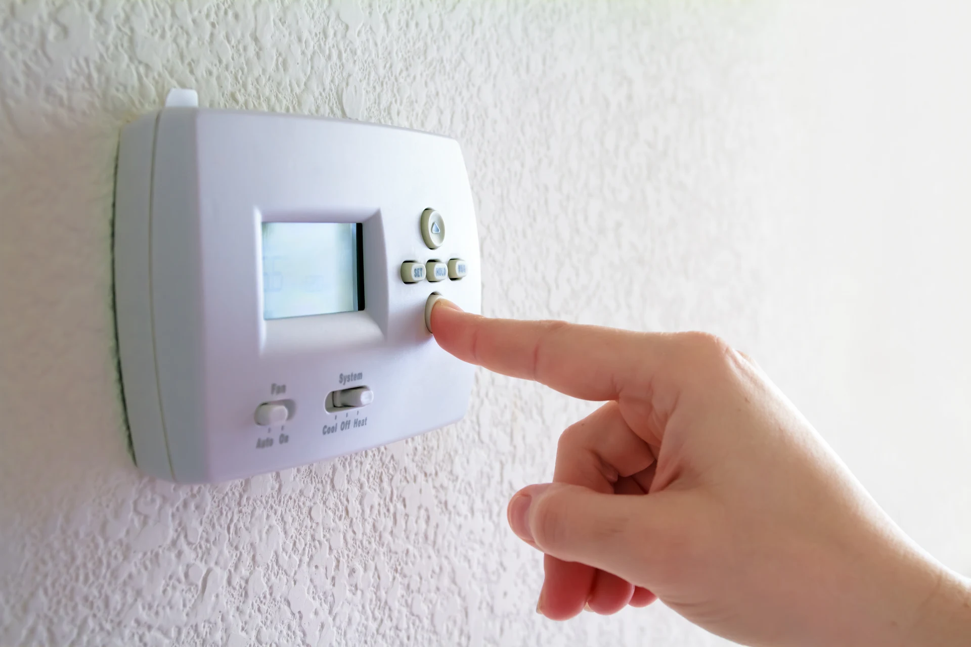 person operating a thermostat using buttons