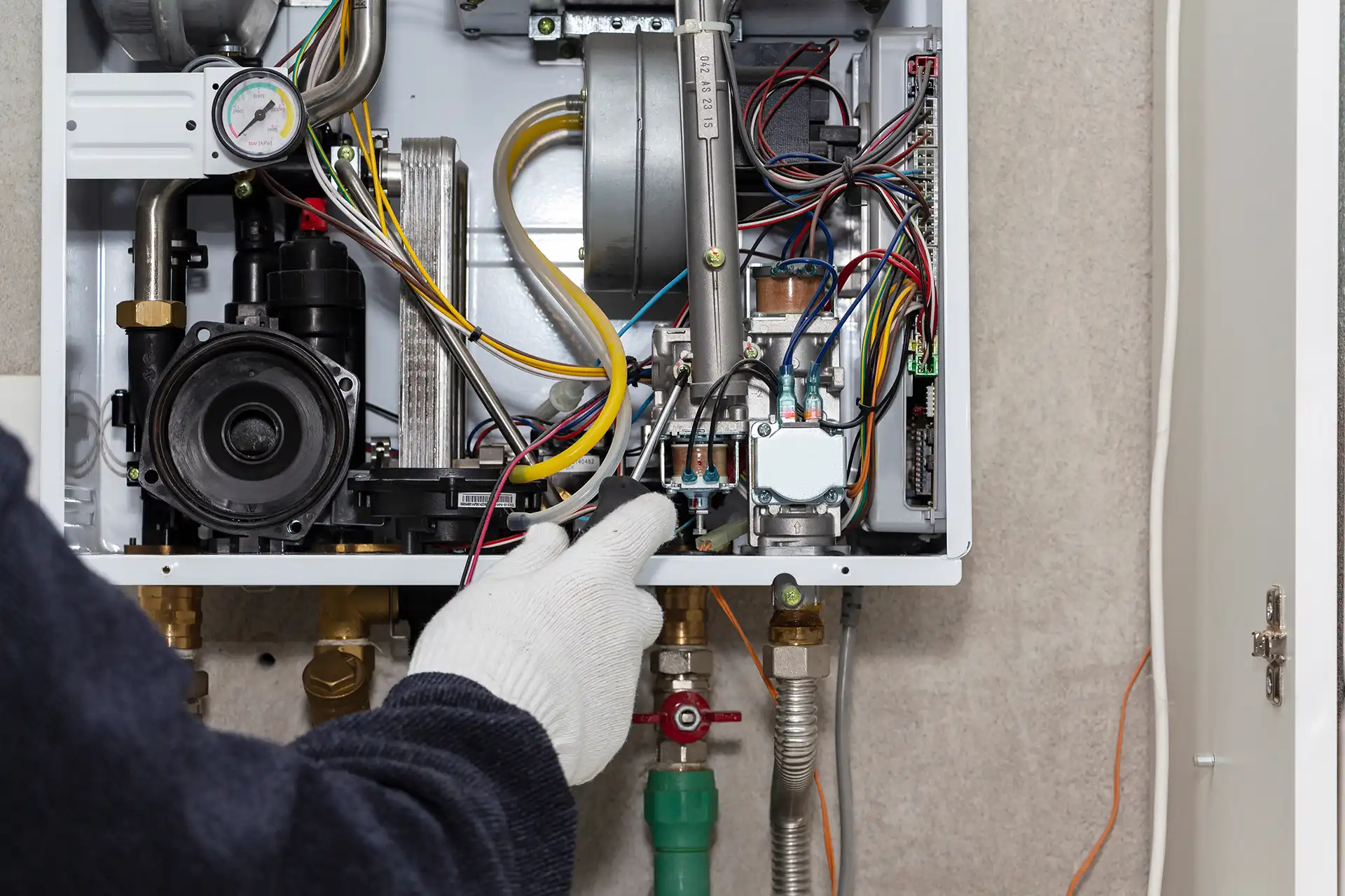 Technician repairing the open control panel of a gas boiler